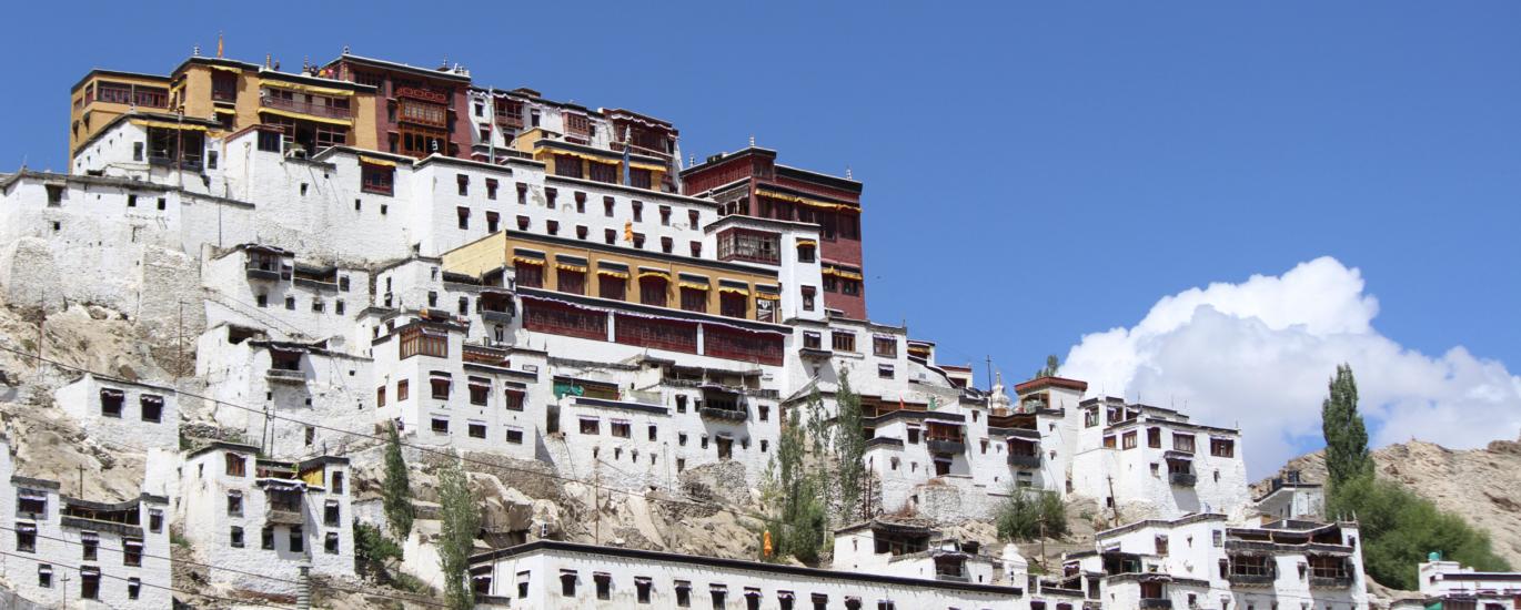 A breathtaking front view of Thiksey Monastery in Leh, Ladakh, showcasing its multi-tiered Tibetan architecture set against the rugged Himalayan landscape.